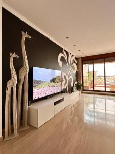 ein Wohnzimmer mit einem TV mit zwei Giraffen an der Wand in der Unterkunft Casa con jacuzzi y piscina con vistas al castillo in Corbera de Alcira