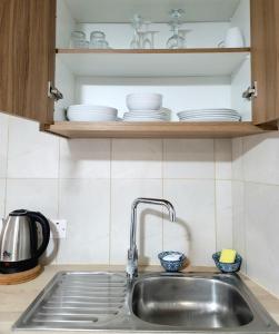 a kitchen sink with plates and bowls on a shelf at Palm Sea Suite 17 in Larnaka