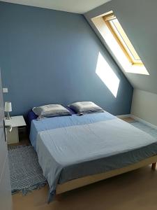 a bedroom with a bed with a blue wall at Maison au calme proche des plages du Golfe du Morbihan in Baden