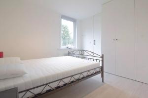 um quarto branco com uma cama e uma janela em Vakantiehuis Belle em Nieuwpoort