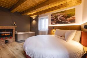 a bedroom with a large white bed and a fireplace at Granduca Mountain Wellness Apartments Campigna in Campigna