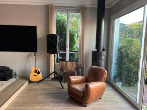 ein Wohnzimmer mit einem TV, einem Stuhl und einer Gitarre in der Unterkunft MON DÉSIR in Saint-Maur-des-Fossés