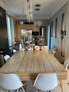 eine Küche mit einem großen Holztisch und weißen Stühlen in der Unterkunft MON DÉSIR in Saint-Maur-des-Fossés