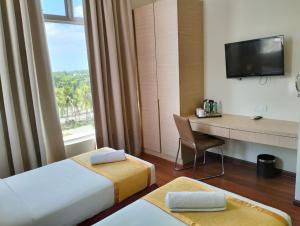 a hotel room with two beds and a desk and a television at Sunflower World Hotel in Kuala Selangor