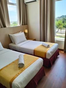 2 Betten in einem Hotelzimmer mit Fenster in der Unterkunft Sunflower World Hotel in Kuala Selangor