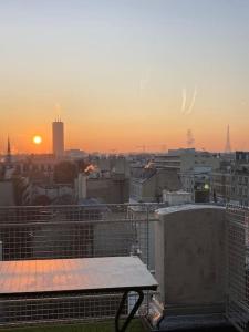 a view of a city at sunset with a bench at 2 bedrooms in the sky ! in Neuilly-sur-Seine
