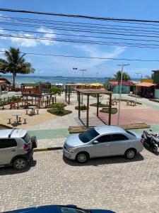 two cars parked in a parking lot near the beach at Flat Beira Mar no Condomínio Diver in Vera Cruz de Itaparica