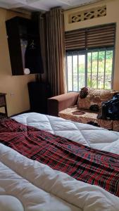 a bedroom with two beds and a couch and a window at COLIBRI VILLA City Center in Gisenyi