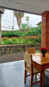 a wooden table and chairs with a garden in the background at COLIBRI VILLA City Center in Gisenyi