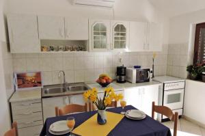 a kitchen with a table with yellow flowers on it at Apartmani Frakić in Veli Rat