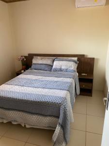 Schlafzimmer mit einem Bett mit blauer und weißer Bettwäsche und Kissen in der Unterkunft Flat Beira Mar no Condomínio Diver in Vera Cruz de Itaparica