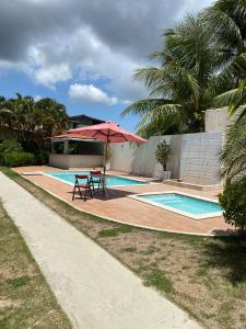 uma mesa com um guarda-sol ao lado de uma piscina em Flat Beira Mar no Condomínio Diver em Vera Cruz de Itaparica