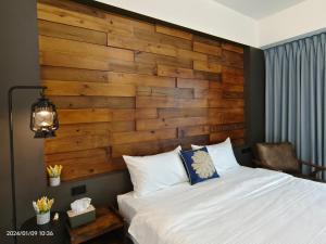 1 dormitorio con 1 cama con pared de madera en 墾丁堡雅1號 電梯包棟民宿, en Hengchun