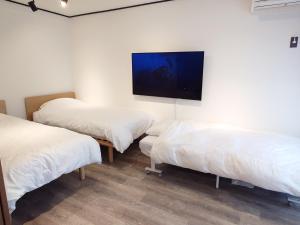 um quarto com duas camas e uma televisão na parede em NIYS apartments 53 type em Tóquio