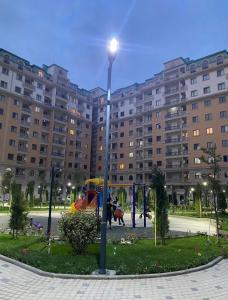 un pôle lumineux avec une aire de jeux en face d'un grand bâtiment dans l'établissement House with sea view, à Soumgaït