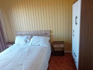 1 dormitorio con 1 cama con sábanas y almohadas blancas en Cabaña Curanipe Playa, en Curanipe