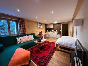 a living room with a green couch and a bed at One Bedroom with mountain and garden view ground floor of Chalet Solaria in Zweisimmen