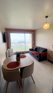 a living room with a table and a couch at Studio Le Mer'Veilleux in Calais