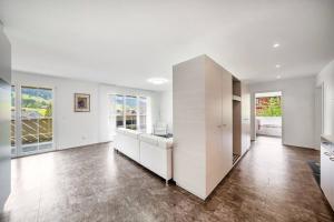 una gran sala de estar con paredes blancas y suelos de madera. en helle moderne 3,5-Zimmer-Wohnung 84m2, en Oberiberg