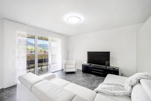a white living room with a white couch and a tv at helle moderne 3,5-Zimmer-Wohnung 84m2 in Oberiberg