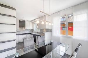 a white kitchen with a glass table and chairs at helle moderne 3,5-Zimmer-Wohnung 84m2 in Oberiberg