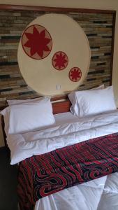 una camera da letto con letto, lenzuola e cuscini bianchi di COLIBRI VILLA City Center a Gisenyi