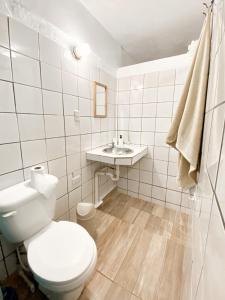 een witte badkamer met een toilet en een wastafel bij La Hacienda Hostel in Las Galeras