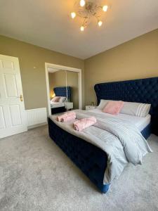 um quarto com uma cama azul com almofadas cor-de-rosa em The Naburn - 3 Bed House with Free Parking & Close to City Centre em Glasgow