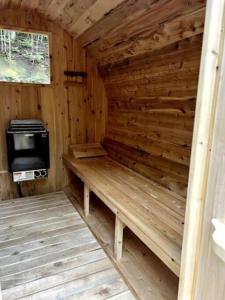 een houten hut met een bank en een fornuis bij Lux Winter Getaway with Hot Tub, Sauna, EV charger in Haliburton