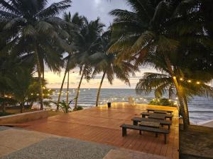 una terraza de madera con bancos, palmeras y el océano en Suites de Lujo Playa Azul, en Tonsupa