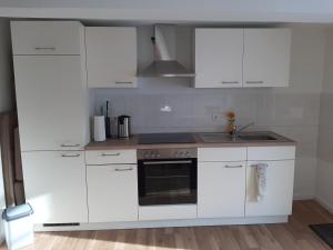 a white kitchen with white cabinets and a sink at Gemütliche Ferienwohnung der Familie Hüther in Göttingen