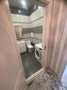 a bathroom with a toilet and a sink and a washing machine at ЖК Green Plaza in Aktau