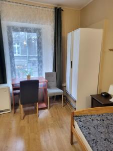 ein Wohnzimmer mit einem Tisch und einem Kühlschrank in der Unterkunft Hostel Gliwice Centrum in Gliwice