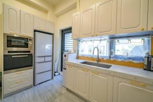 a kitchen with white cabinets and a sink and a refrigerator at Wei Yu's Home Villa in Dongshan