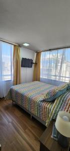 um quarto com uma cama e 2 janelas grandes em Personal Aparts Bellas Artes em Santiago