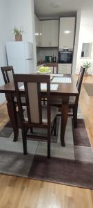 a wooden dining room table with chairs and a kitchen at Apartman 022 in Smederevska Palanka