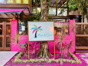 una señal frente a un edificio rosa con una palmera en Pousada Agua de Coco, en Arraial d'Ajuda