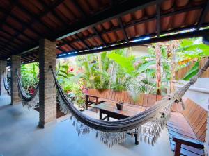 a hammock in a room with a table and benches at Pousada Agua de Coco in Arraial d'Ajuda