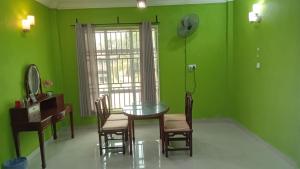 a dining room with green walls and a table and chairs at D' Bunga Hotel Bukit Bunga Bilik Family Deluxe in Batu Karang