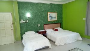 2 camas en una habitación con paredes verdes en D' Bunga Hotel Bukit Bunga Bilik Family Deluxe en Batu Karang