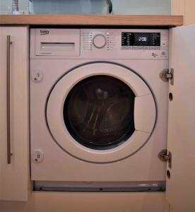 a washing machine in a cabinet in a kitchen at Lovely Annexe near Surbiton/Kingston, SW London in Chessington