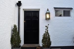 a black door on a white house with two plants at Lovely Annexe near Surbiton/Kingston, SW London in Chessington
