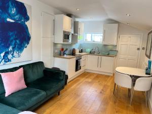 a living room with a green couch and a kitchen at Lovely Annexe near Surbiton/Kingston, SW London in Chessington