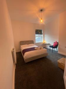 a bedroom with a bed and a chair and a window at SkylinesAirbnb in Stoke on Trent