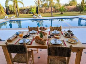 uma mesa com comida ao lado de uma piscina em Villa Rahma em Marrakech
