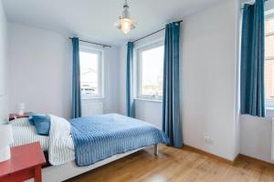 a bedroom with blue curtains and a bed with a desk at Apartament Łajba Łeba z basenem i kortem tenisowym in Łeba +38 photos