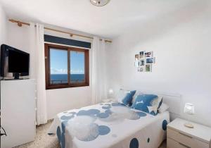 1 dormitorio con cama, ventana y TV en Costa Azul apartamento con vista, en Candelaria