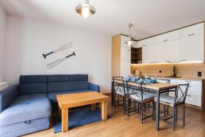 a living room with a blue couch and a table at Apartament Łajba Łeba z basenem i kortem tenisowym in Łeba