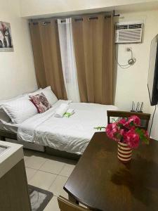 a room with a bed and a table with flowers on it at Pierrecondotel in Manila