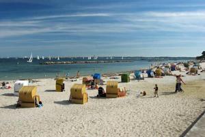 un grupo de personas en una playa con sillas y sombrillas en Sofort am Strand!, en Kiel